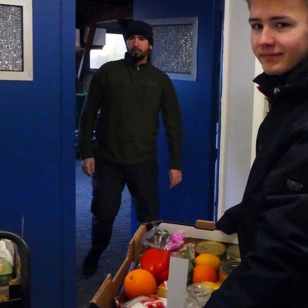 Justus trägt eine Kiste mit Spenden bei der Tafel.