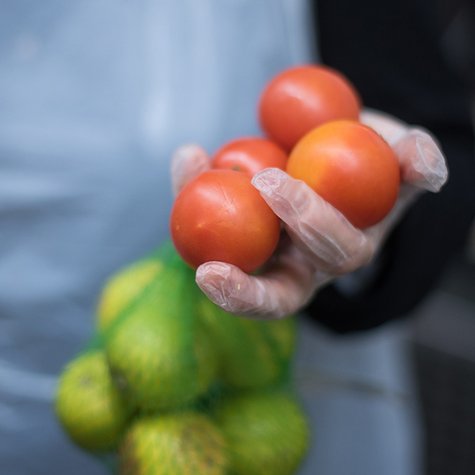 Eine Freiwillige der Tafel hält Tomaten und Zitronen in der Hand.